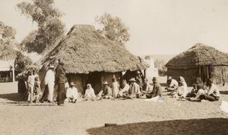 Aboriginal people outside thatched huts 1923